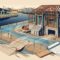 Partially built home on a raised foundation beside a canal with drainage swales and survey stakes.